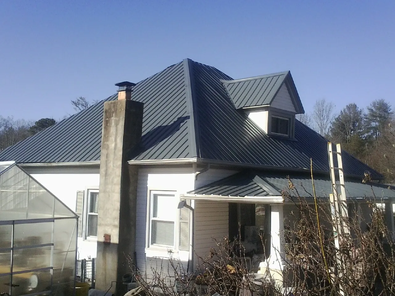 Dark blue standing seam metal roof on a white farmhouse with dormer — Slate & Tile Roof Repair by Roofing Brothers in McMinnville