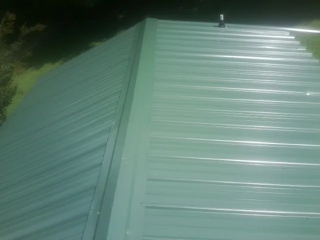New green metal panels meeting at the ridge of a roof — Flat Roof Repair work by our crew in McMinnville