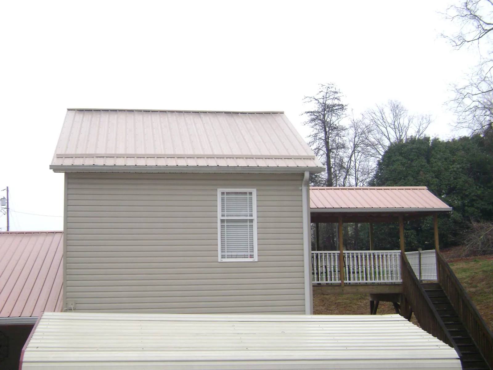 Tan metal roofs on a two story addition and attached porch, from a Roof Replacement job in McMinnville